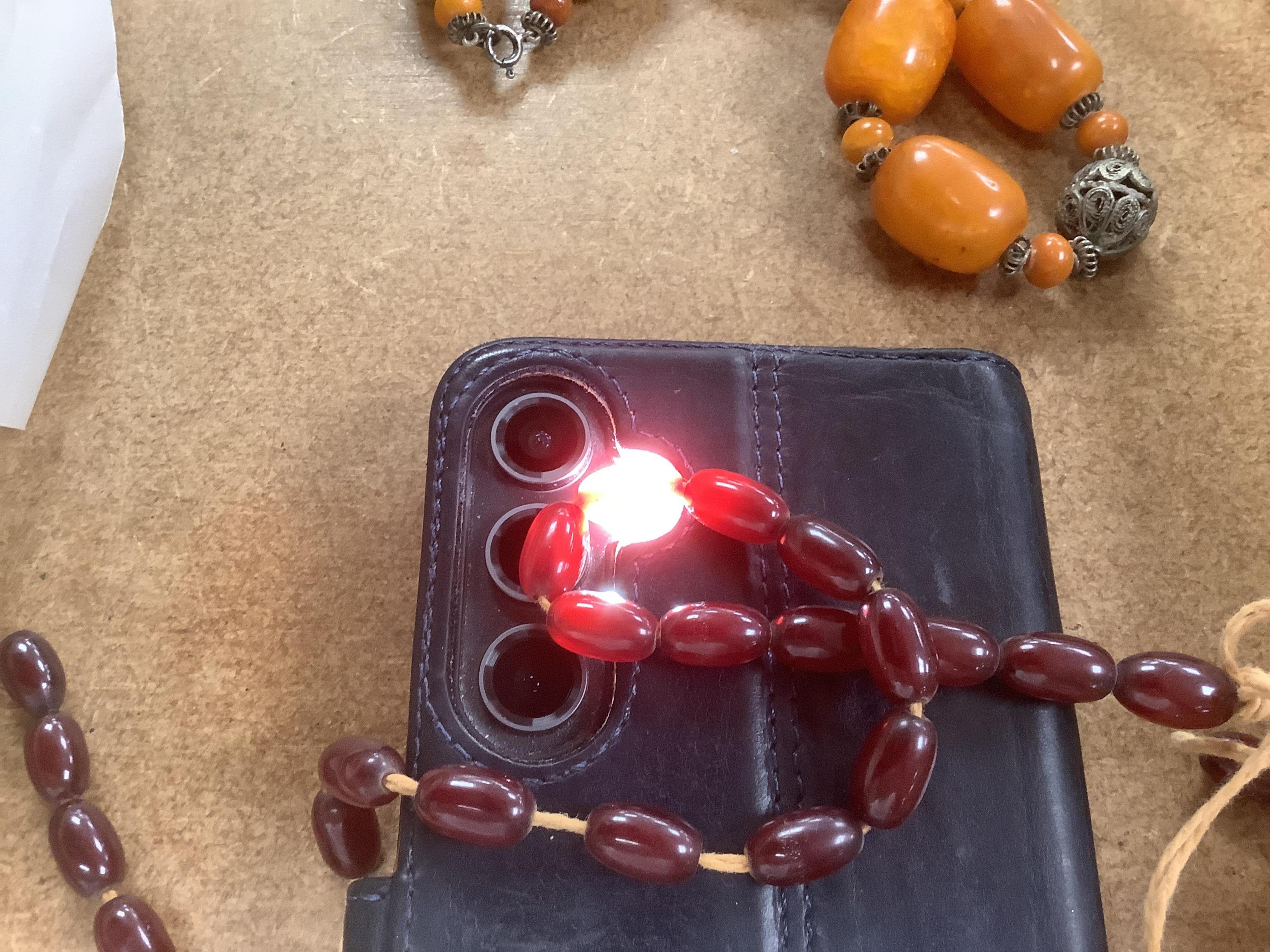 A single strand amber bead necklace, with filigree metal spacers, 48cm, gross 84 grams, together with a group of loose graduated simulated cherry amber beads, gross weight 117 grams.